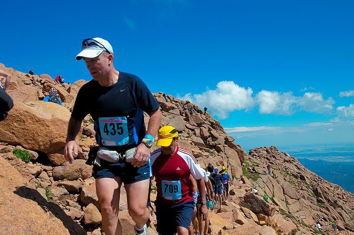 Athletes wearing numbered race bibs climbing the Pikes Peak Ascent